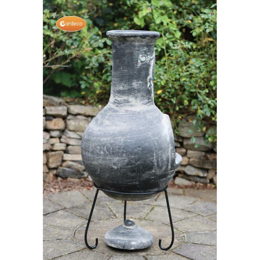 Back of Iguana X-Large Mexican Chiminea Grey | Handmade Clay on a stand with a stone wall and greenery in the background