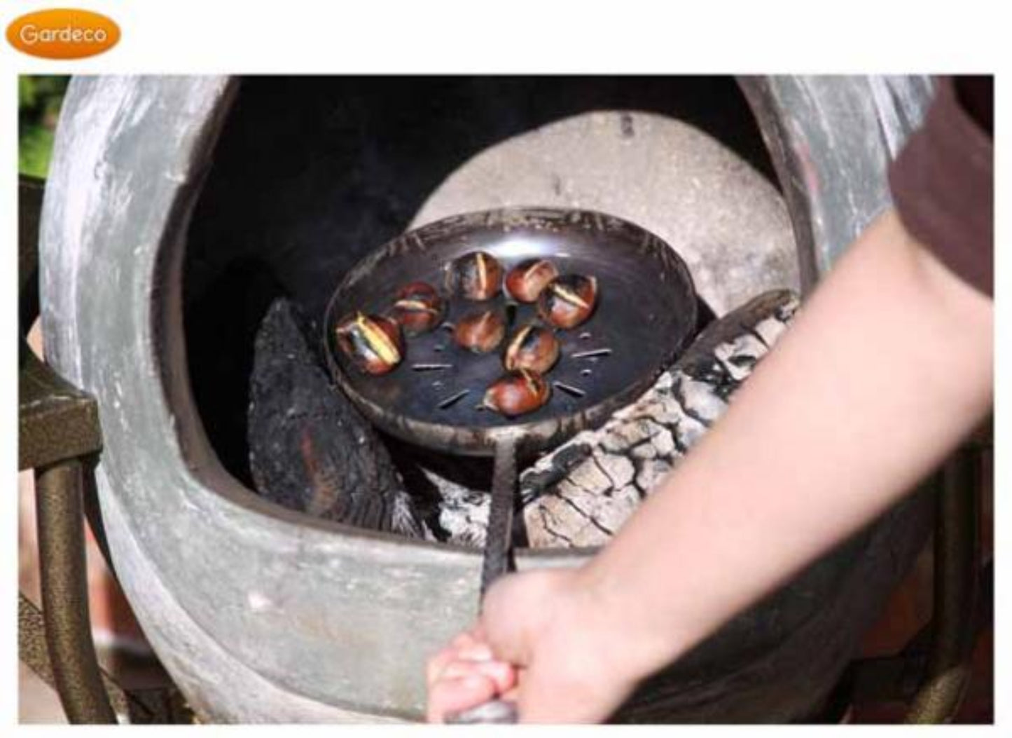 Person roasting chestnuts in a pan over an open fire