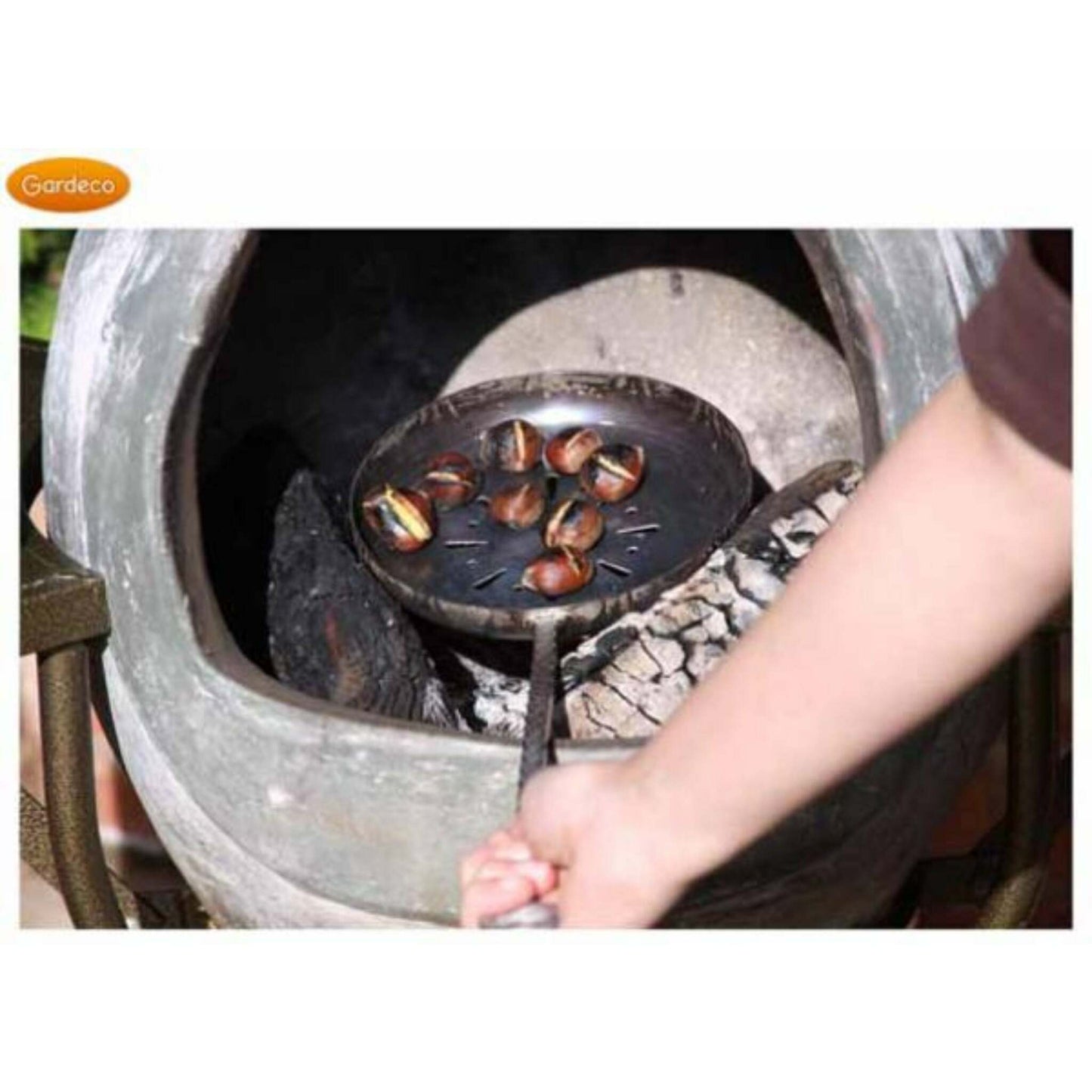 Person roasting chestnuts in a pan over an open fire