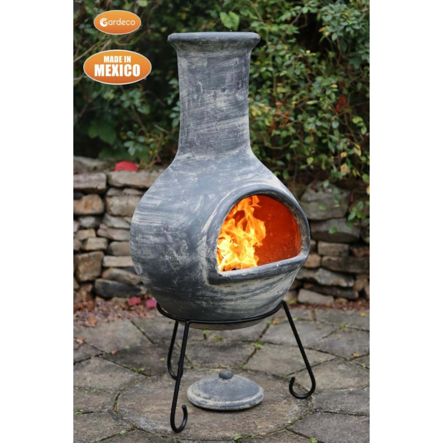 Decorative outdoor fireplace with flames inside, made in Mexico, on a stone patio.