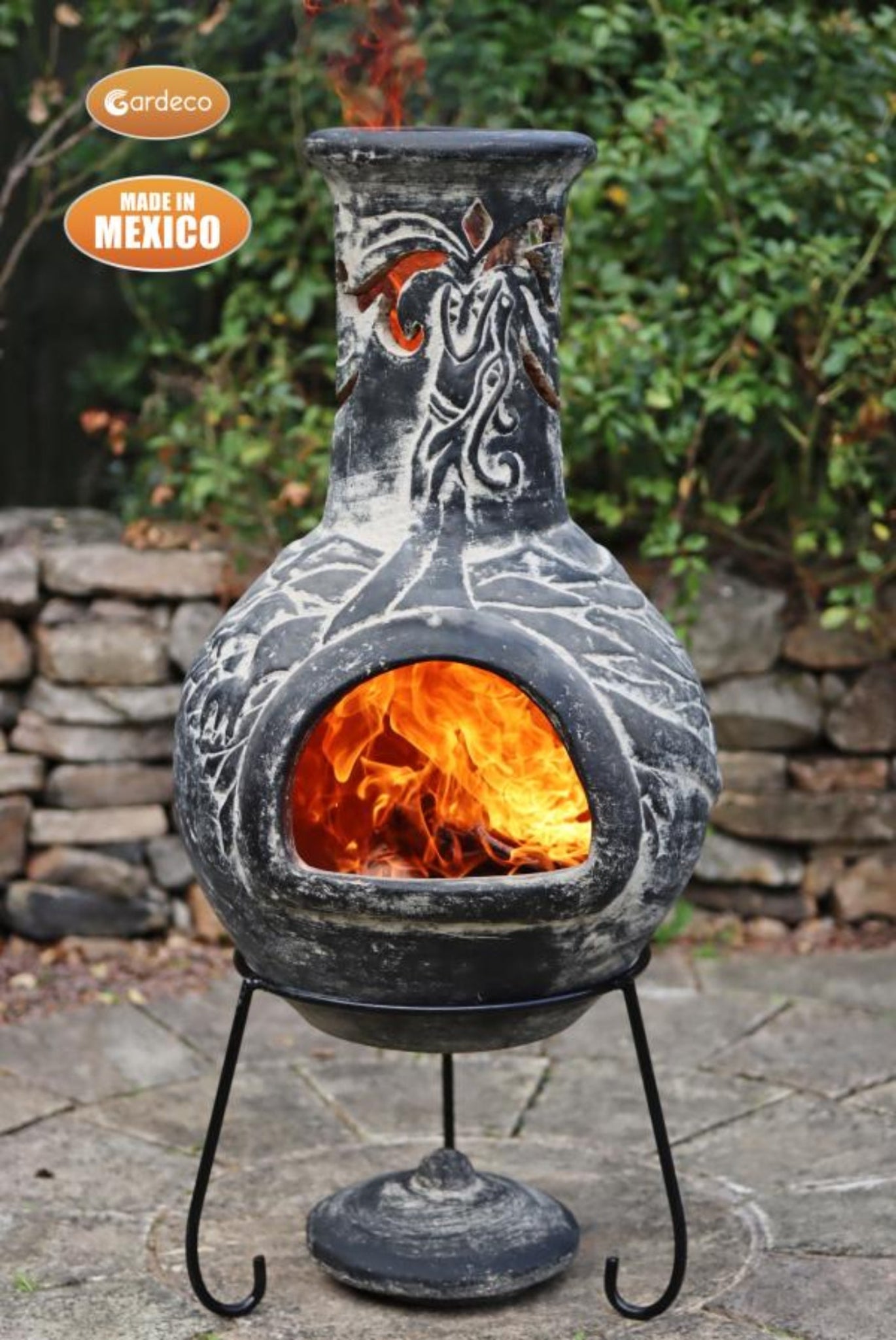 Decorative outdoor fireplace with flames inside, made in Mexico, on a stone patio.