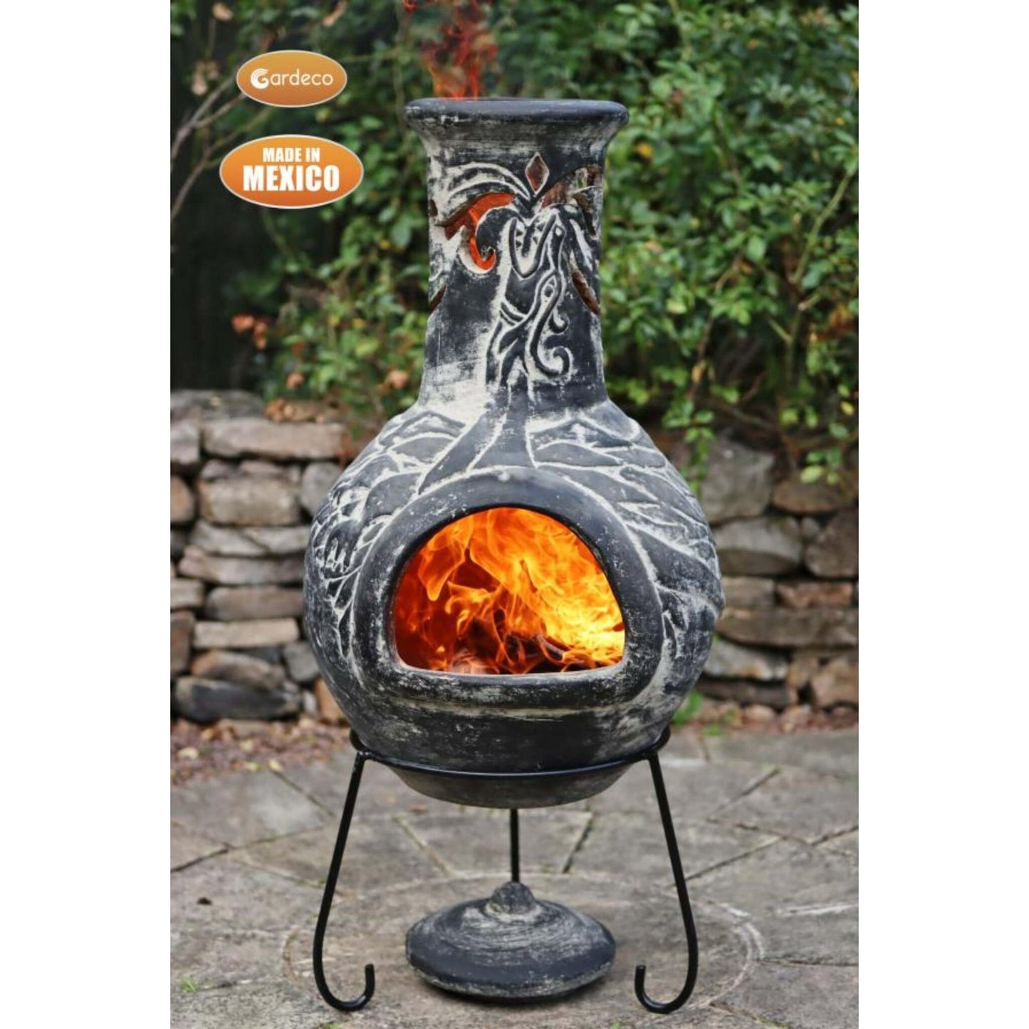 Decorative outdoor fireplace with flames inside, made in Mexico, on a stone patio.