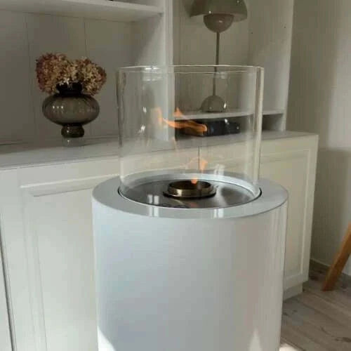 White portable fireplace with clear glass cover on a wooden floor.