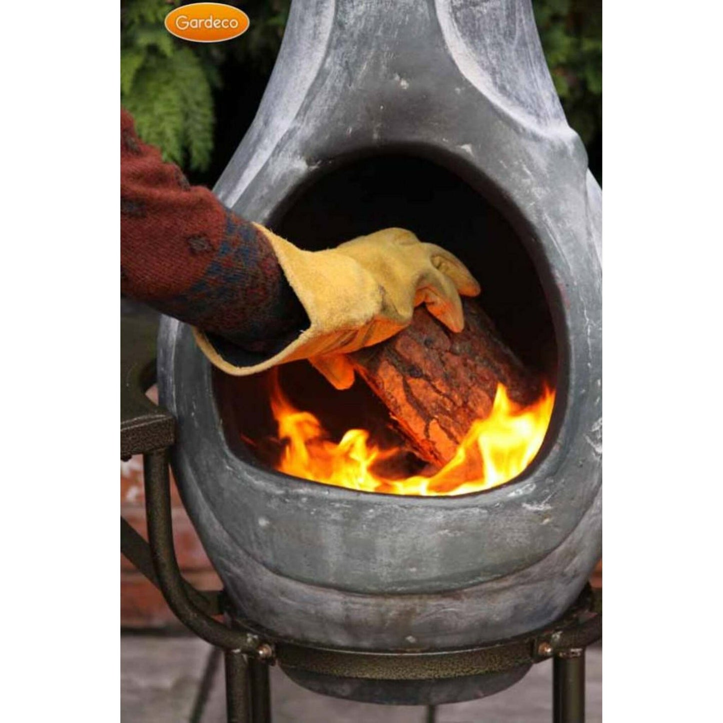 Person lighting a fire in a chiminea with fire resistant gloves on