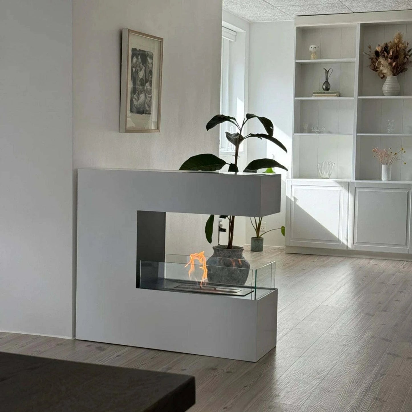 Modern white fireplace with glass front in a living room setting.