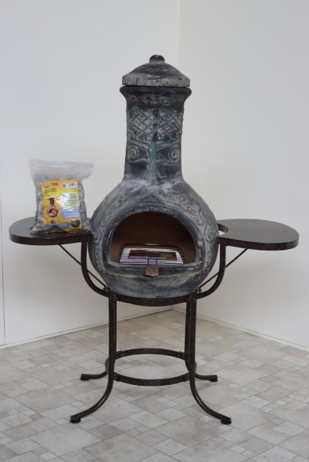 Decorative outdoor fireplace with a small table on a tiled floor.