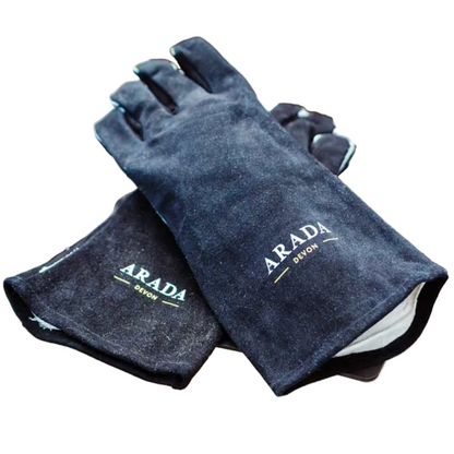 A pair of dark charcoal gray leather work gloves with 'ARADA DEVON' branding, resting on a white slatted metal table over a wooden deck.