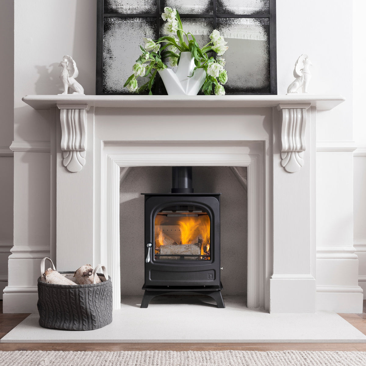 Modern fireplace with a lit stove, white mantel, and decorative elements.