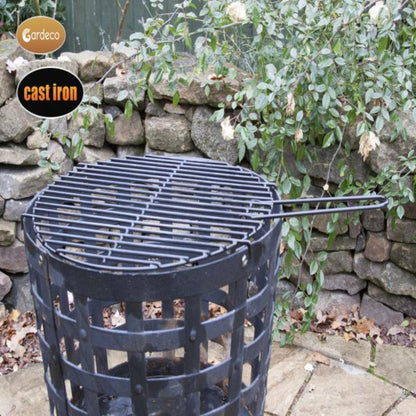 Cast iron grill on a stone patio with a stone wall and plants in the background
