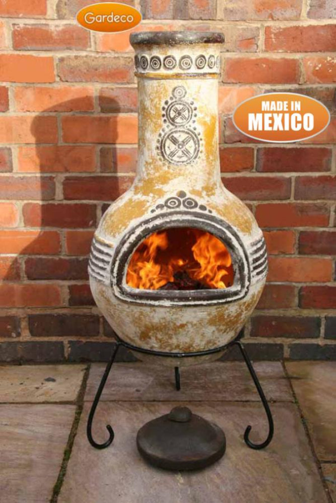 Decorative outdoor fireplace with flames inside, made in Mexico, against a brick wall.