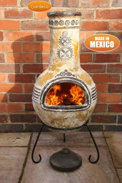 Decorative outdoor fireplace with flames inside, made in Mexico, against a brick wall.