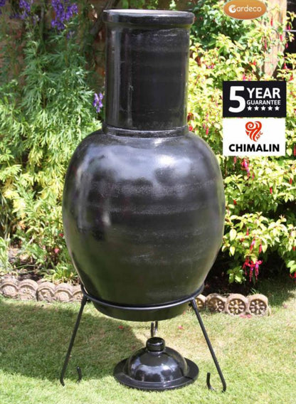Back of Black ceramic chiminea with 'Chimalin' branding on a grassy area with plants in the background.