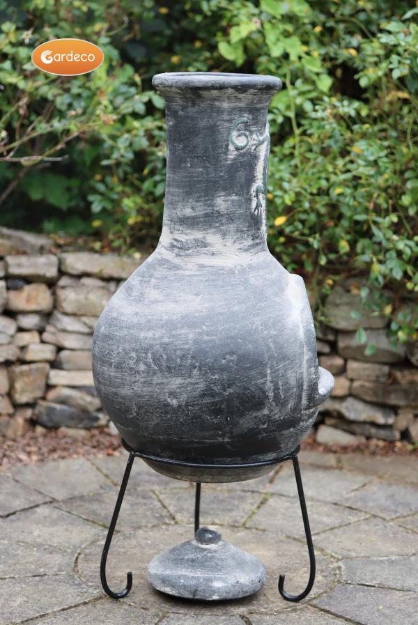 Back of Iguana X-Large Mexican Chiminea Grey | Handmade Clay on a stand with a stone wall and greenery in the background
