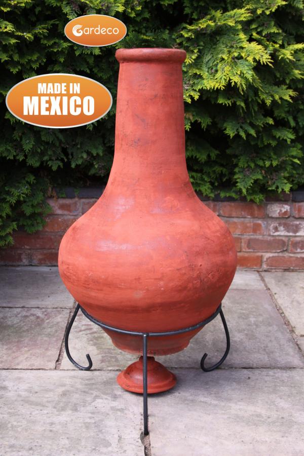 Terracotta chiminea with Gardeco branding and 'Made in Mexico' label against a green bush background.