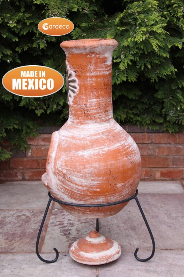 Terracotta pot on a stand with Gardeco branding and 'Made in Mexico' text, against a green bush background.