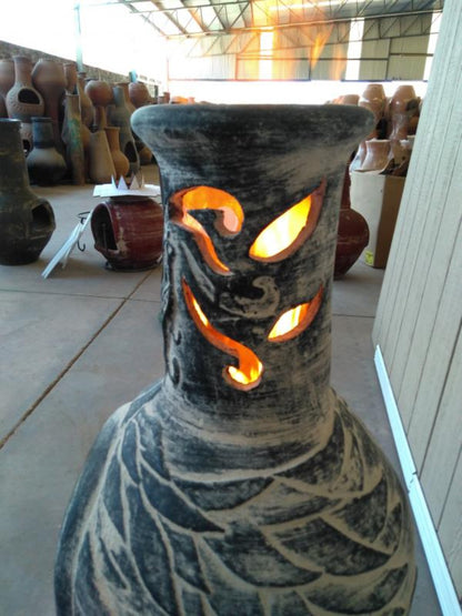 Ceramic chiminea with dragon design glowing inside, surrounded by other chimineas.