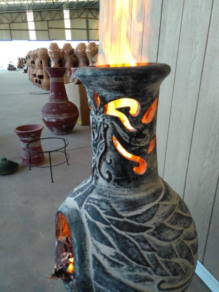 Decorative chiminea with intricate designs and a glowing interior in an indoor setting.
