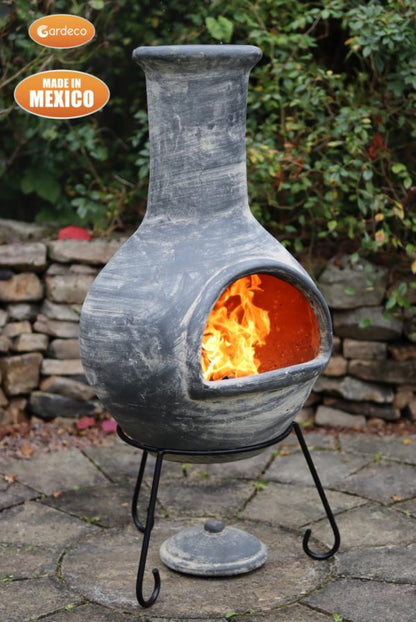 Decorative outdoor fireplace with flames inside, made in Mexico, on a stone patio.