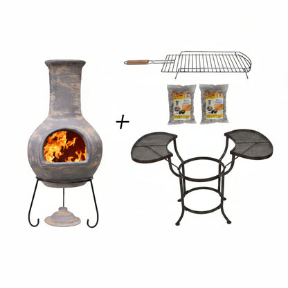 A chimenea fireplace set shown on a white background, including a gray ceramic chimenea with an open fire, a metal grill rack, two bags of lava stones, and a black metal crade with two mesh side tables. A plus sign between the items suggests a bundle.