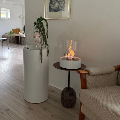 Modern living room with a white cylindrical air purifier, a small round table with a fire pit, and a gray sofa.