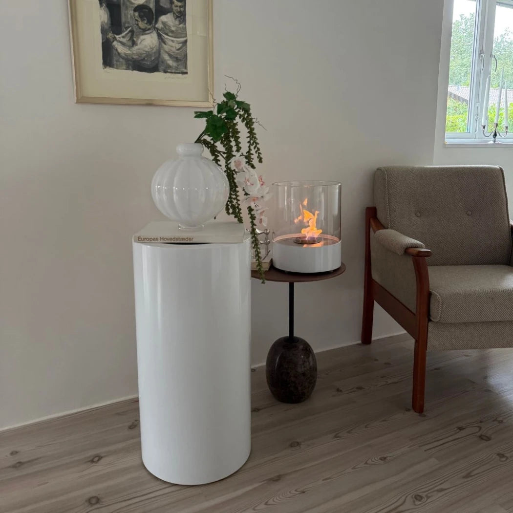 Living room with a white cylindrical table, fire pit, and gray sofa.