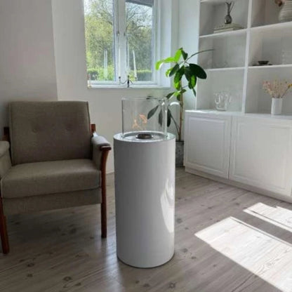 Modern living room with a cylindrical white fire pit and a plant.
