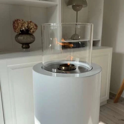 White portable fireplace with clear glass cover on a wooden floor.