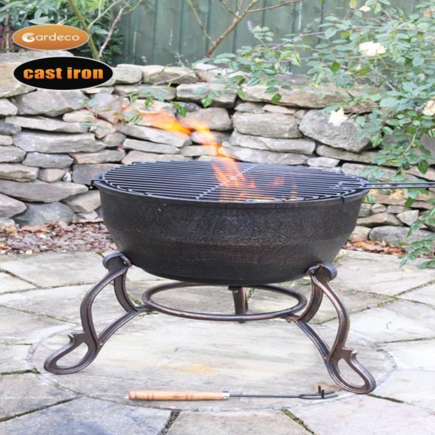 Cast iron fire pit with flames on a stone patio, Gardeco branding visible.