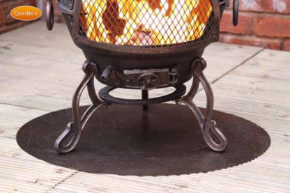 Decorative outdoor fire pit with glowing coals on a floor protector on a wooden deck