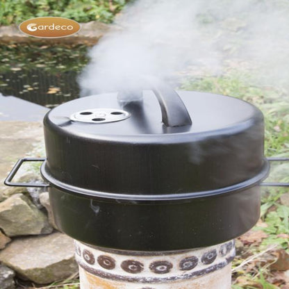 Black smoker with smoke rising, set against a natural outdoor background.