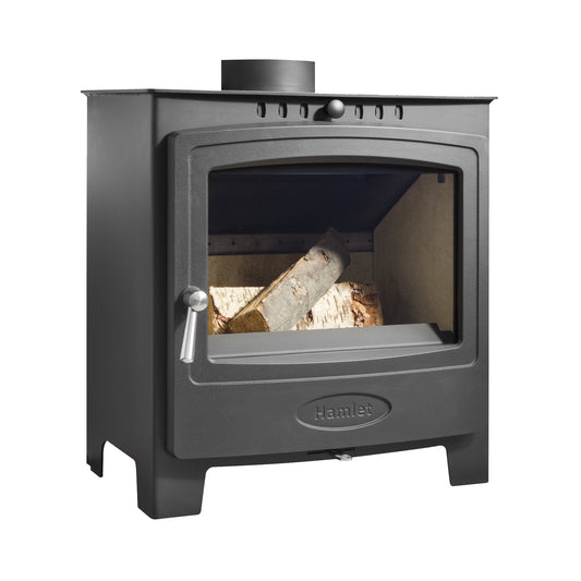 A black cast iron wood-burning stove with a glass door, showing logs inside, on a solid white background. The brand name 'Hamlet' is embossed on the lower front panel.