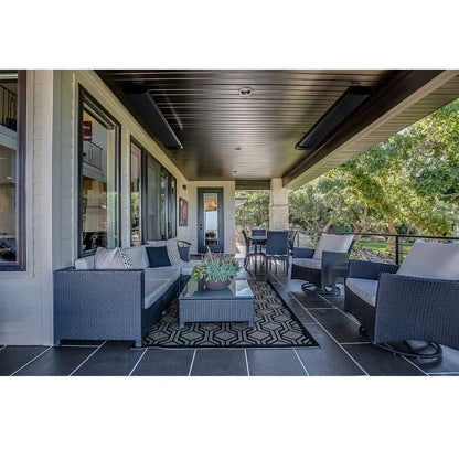 Heatbar Pro 2400 Outside Patio Heater in an outdoor patio with wicker furniture, table, and rug on a tiled floor.