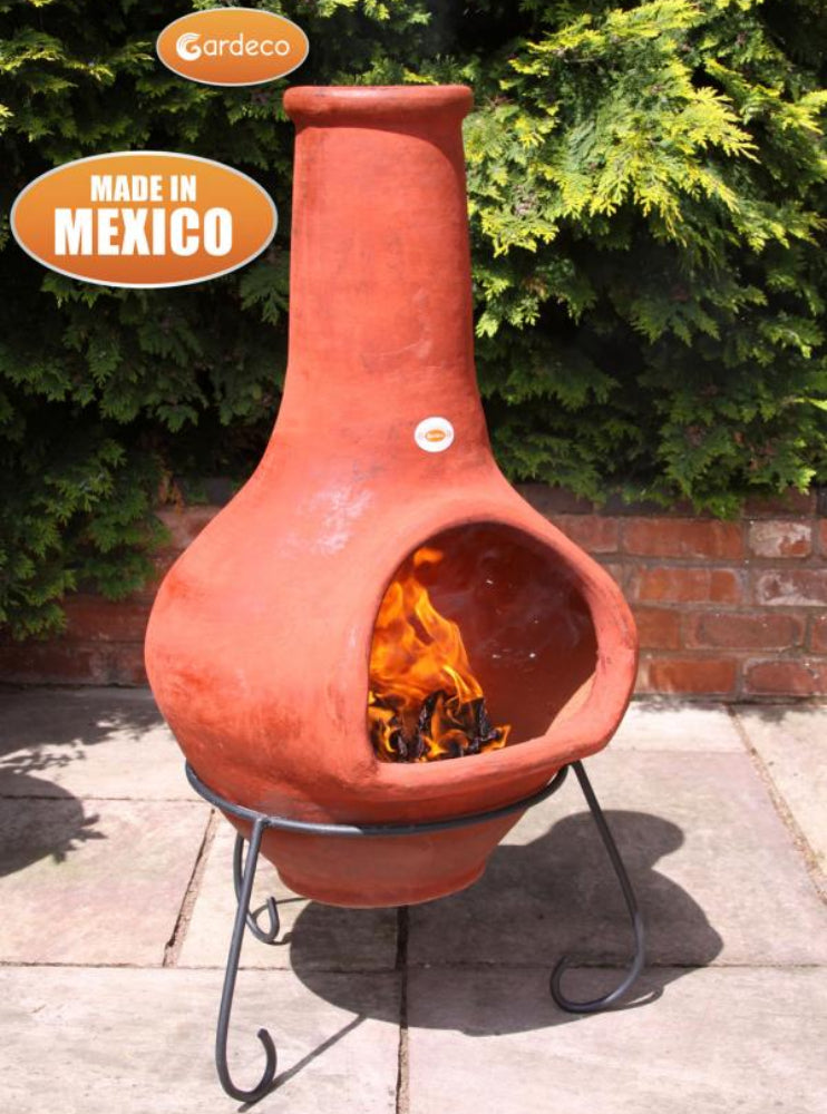 Terracotta chiminea with flames inside, made in Mexico, on a patio.
