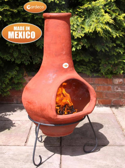 Terracotta chiminea with flames inside, made in Mexico, on a patio.