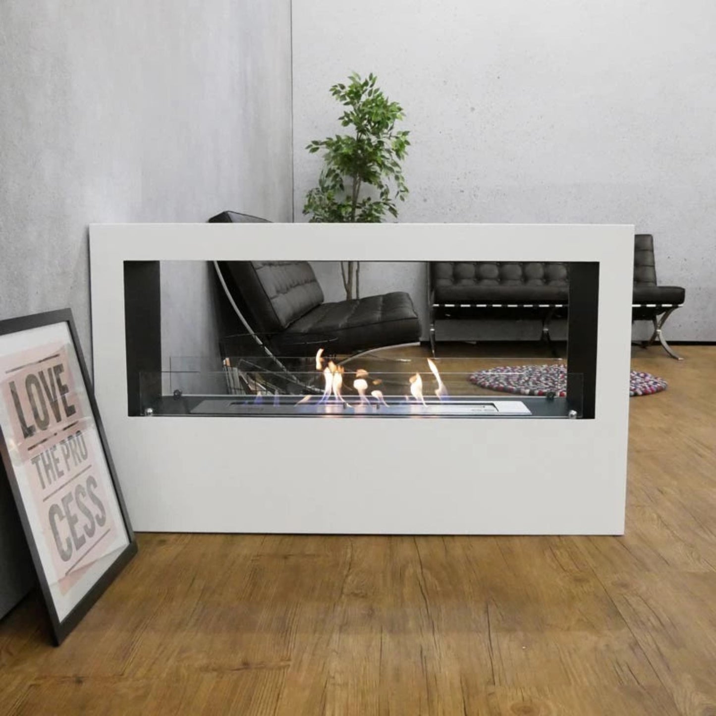 Modern indoor fireplace with a white frame in a room with a couch and plant.