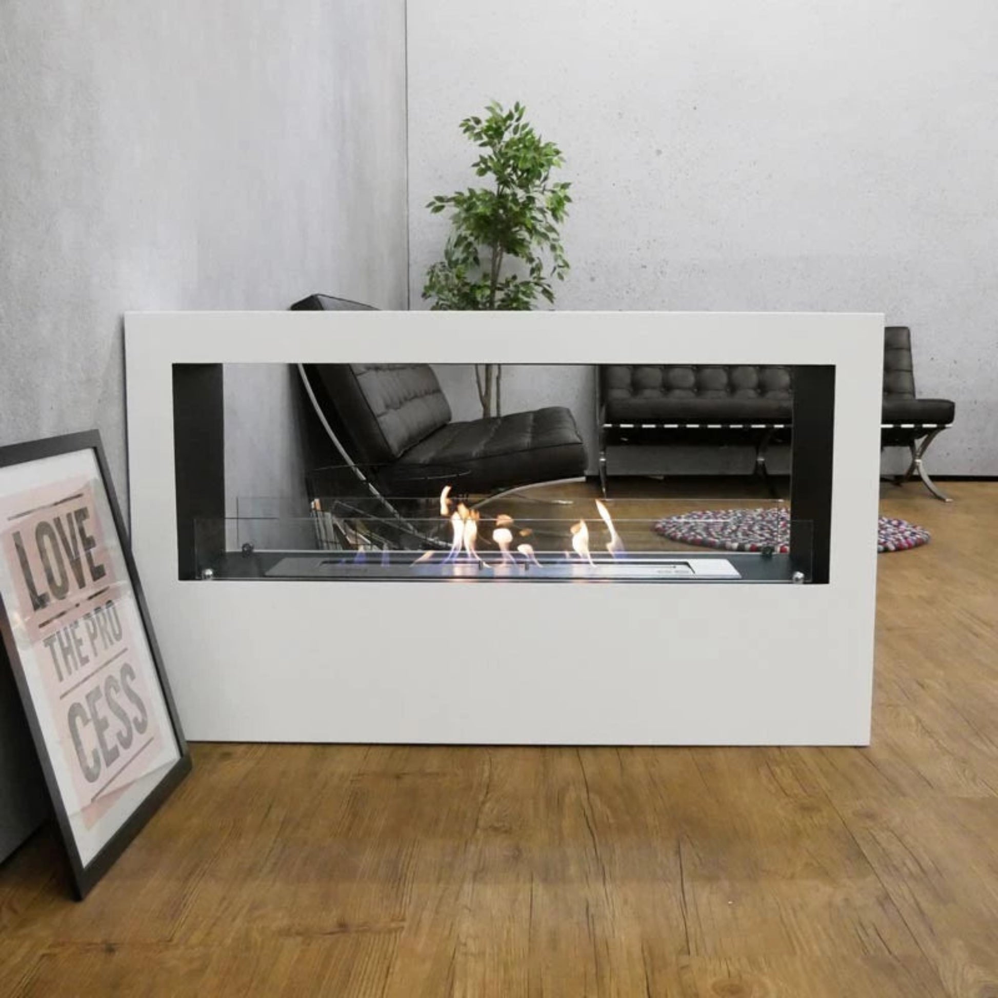 Modern indoor fireplace with a white frame in a room with a couch and plant.
