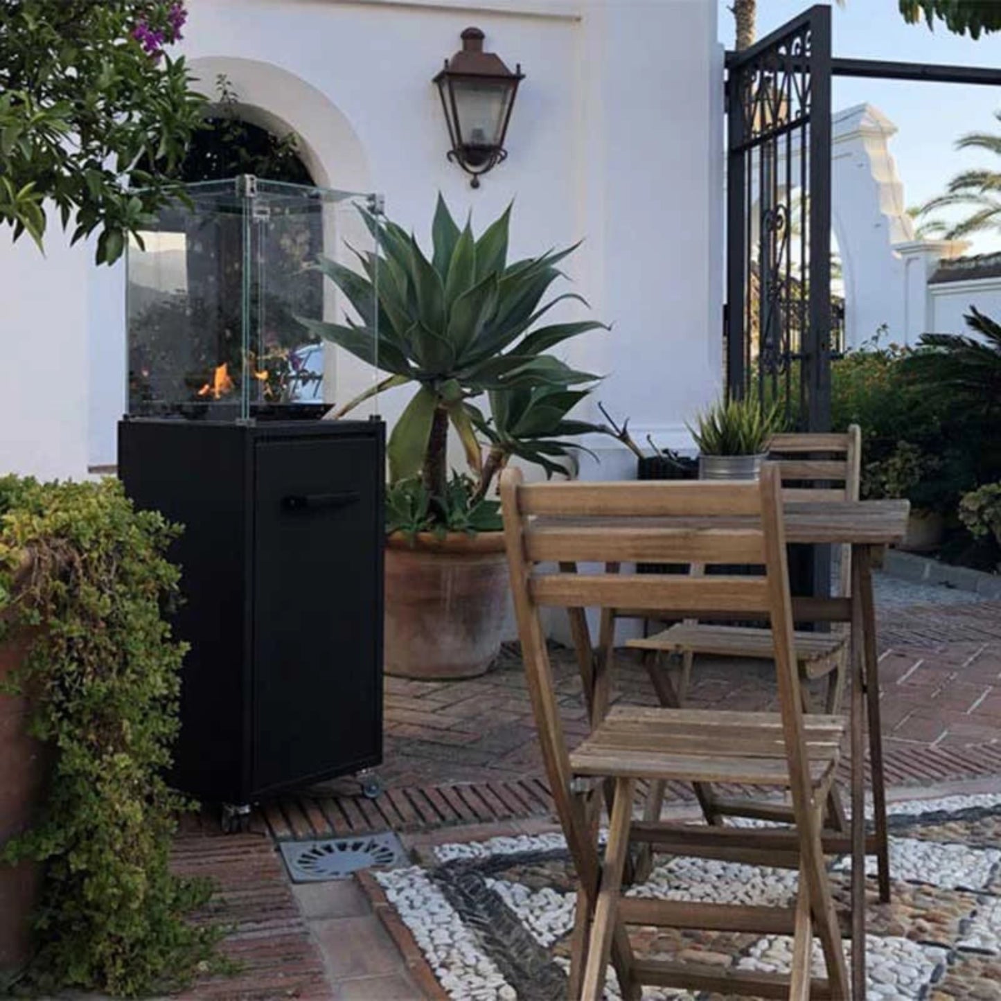 Outdoor patio with a fire pit, table, and chairs in a garden setting.