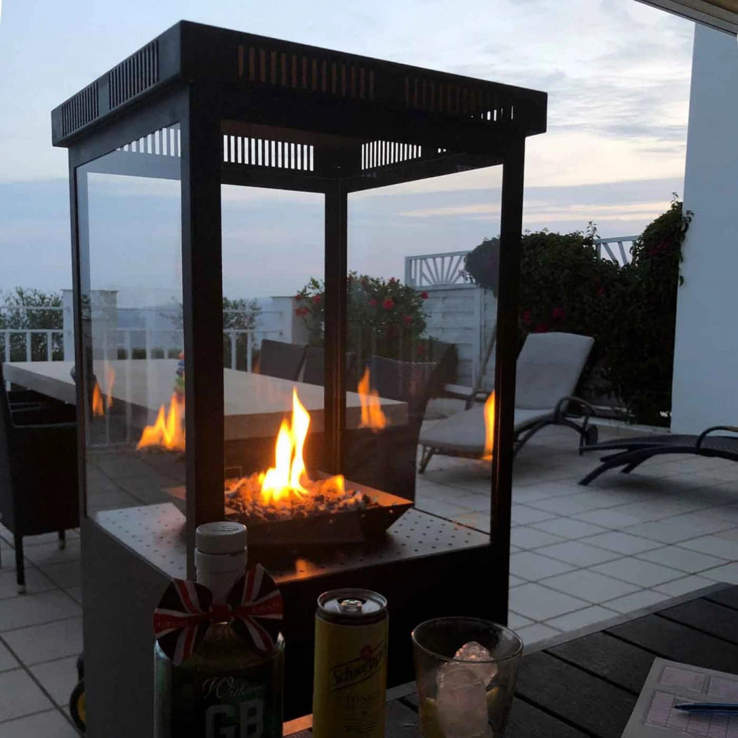 Outdoor patio heater with flames on a patio area with chairs and a table.
