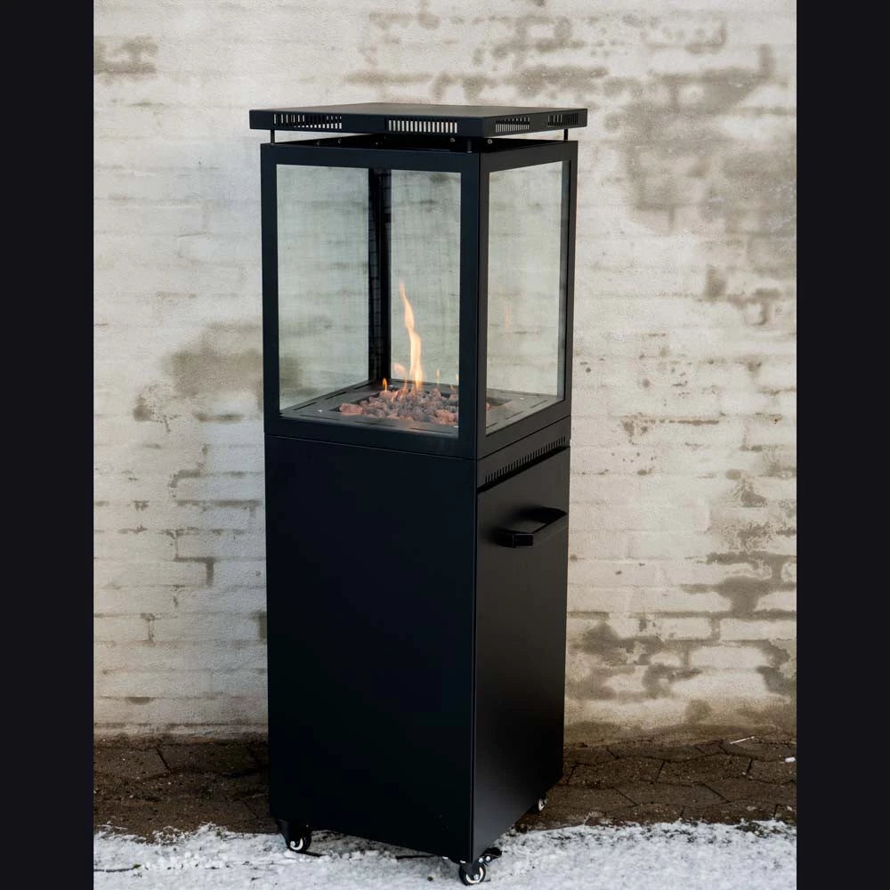 Black outdoor fireplace with glass door against a textured brick wall.