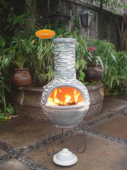 Decorative outdoor fireplace with flames, surrounded by plants and a stone wall.