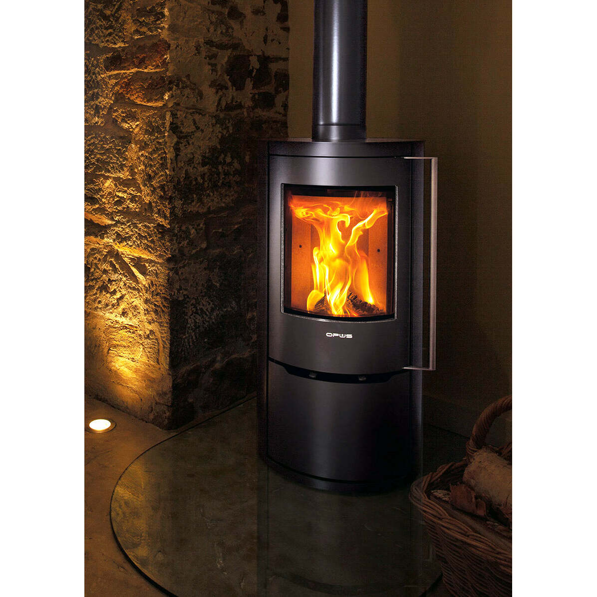 Opus Aria Wood-burning stove with flames inside, set against a stone wall.