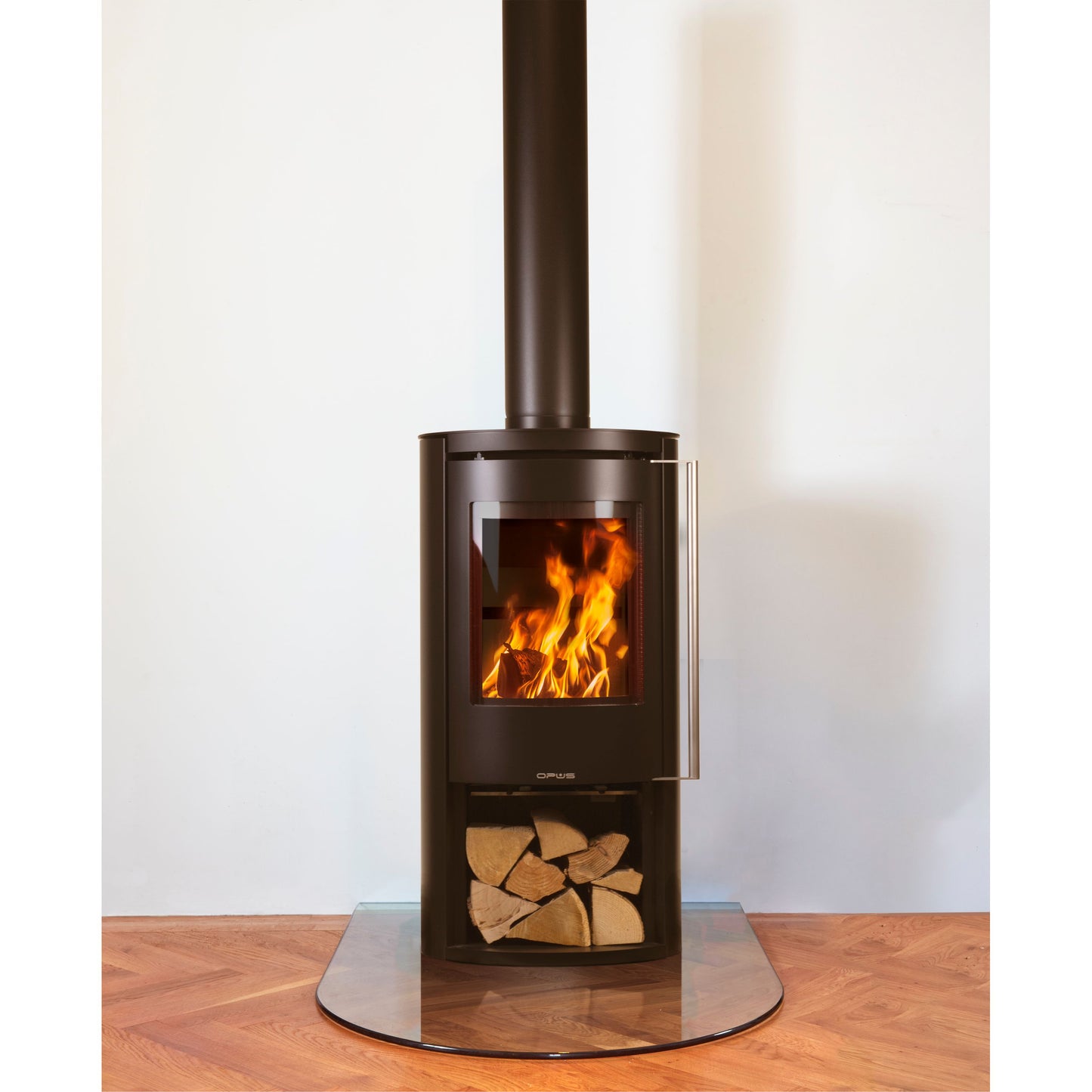 Opus Aria wood stove with flames and log store on a wooden floor against a white wall