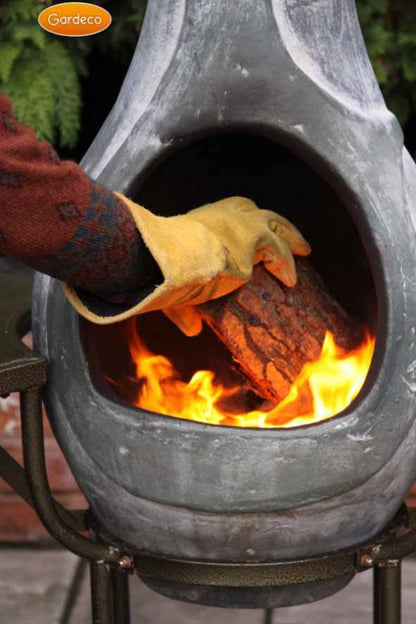 Person lighting a fire in a chiminea with fire resistant gloves on