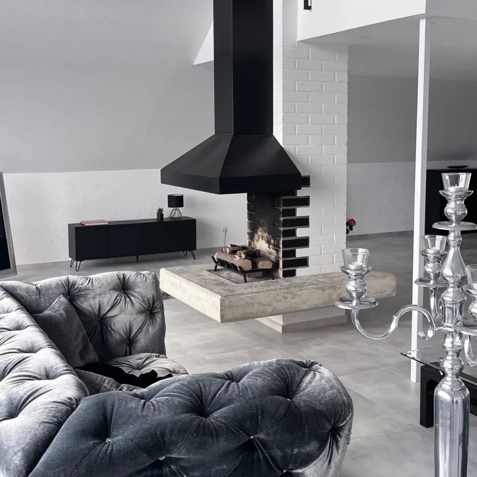Modern living room with gray sofa, black fireplace, and decorative elements.