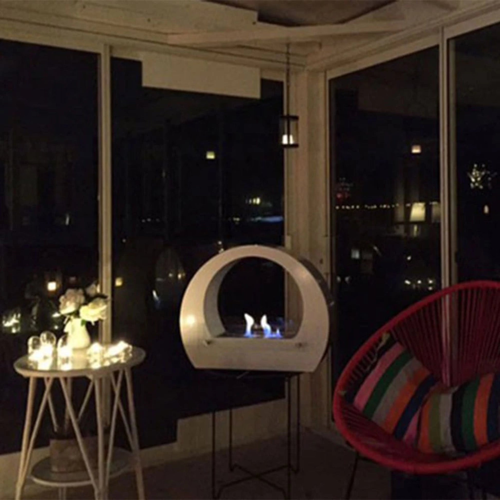 White ScandiFlames Dallas Bio Fireplace with Arch with a colorful chair and small table in a dark setting