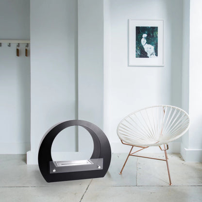 ScandiFlames Dallas Round Bioethanol Fireplace – Black in a white room with a piece of modern art and a photo of a lady.