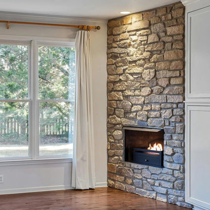 Scandiflames Kingston Freestanding Bioethanol Fireplace Insert in a stone fireplace in a room with a large window and white curtains.