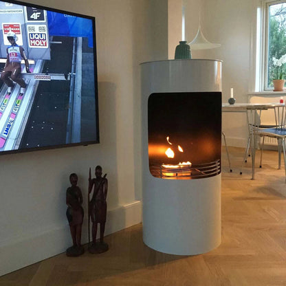 Modern white freestanding fireplace with a lit fire, television displaying a racing event in the background.