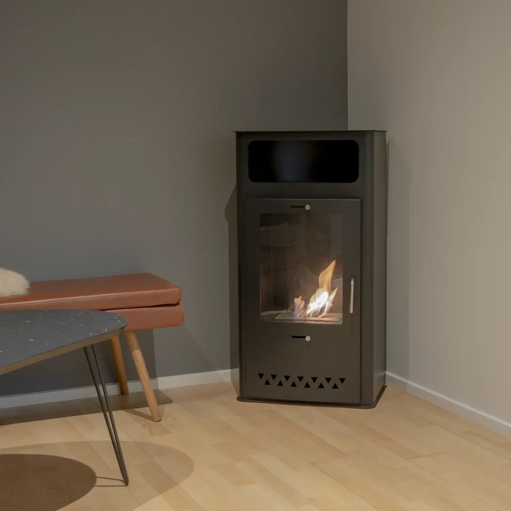Modern freestanding fireplace in a minimalistic room with a bench and table.