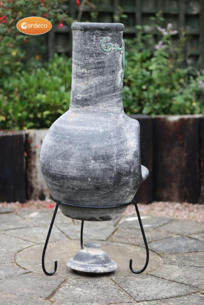 Decorative chiminea on a stand with a garden background